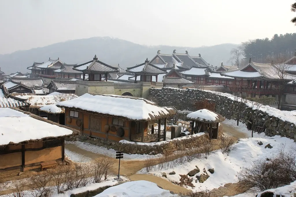 눈이 쌓인 한옥 지붕들이 언덕 아래로 이어진 마을 풍경