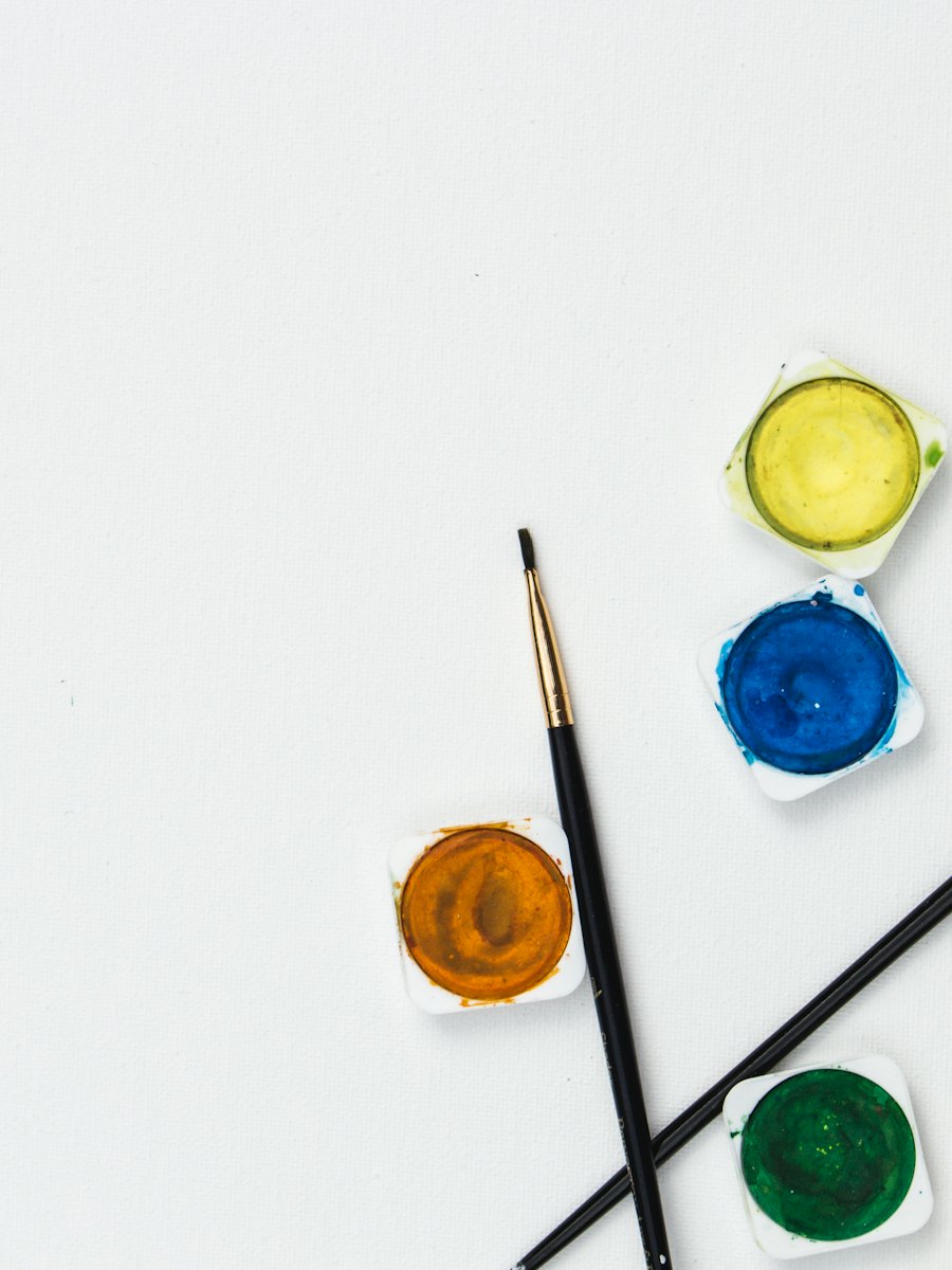 흰 종이 위의 수채 물감 네 가지와 붓 두 자루