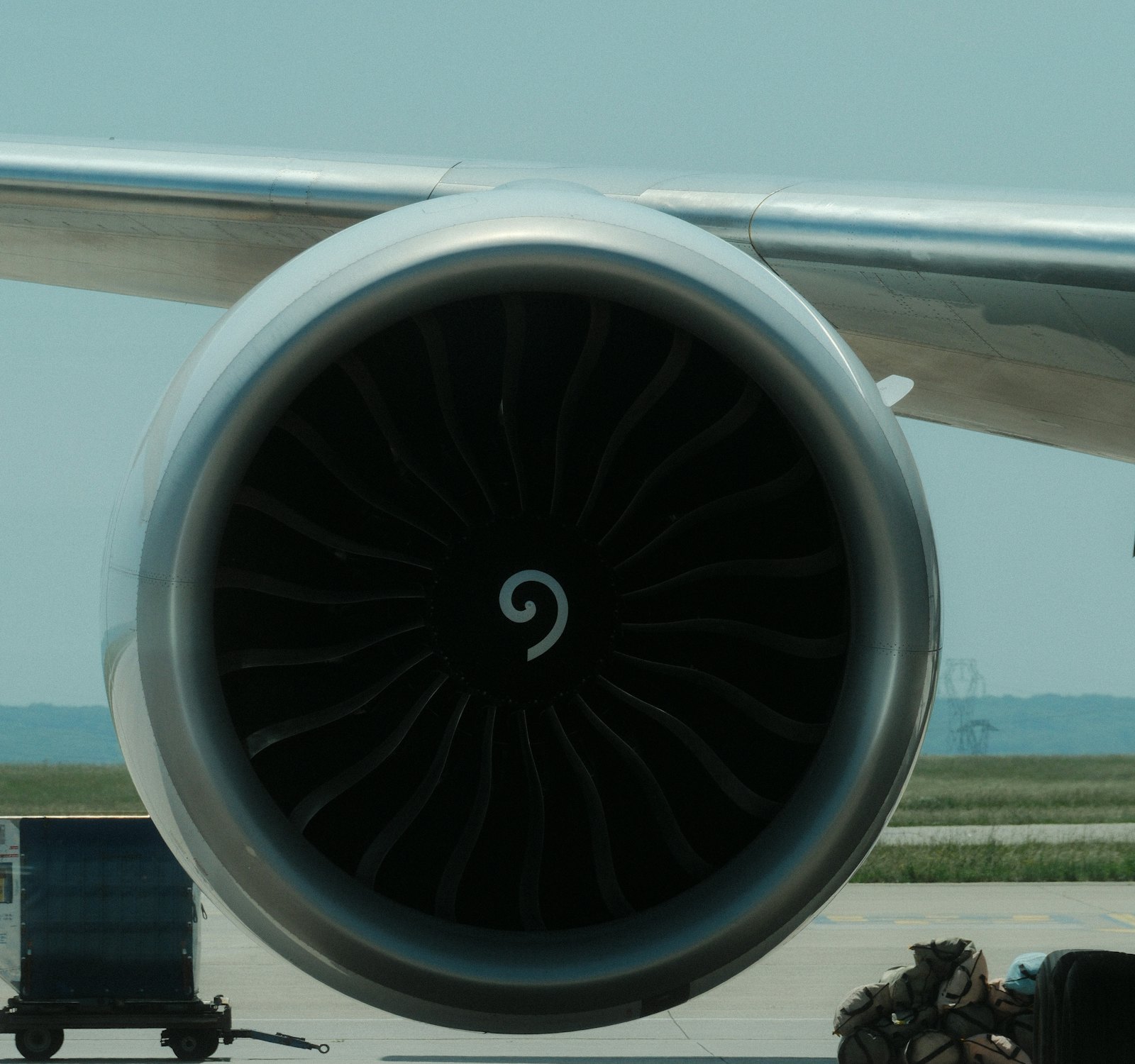 공항 계류장에 선 항공기 엔진 정면과 화물 운반 카트